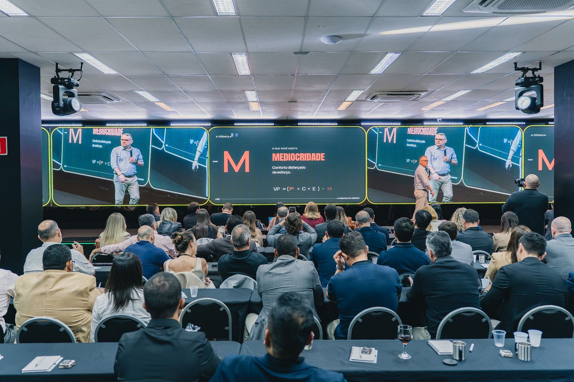 Auditório lotado assistindo à palestra, com a fórmula no telão