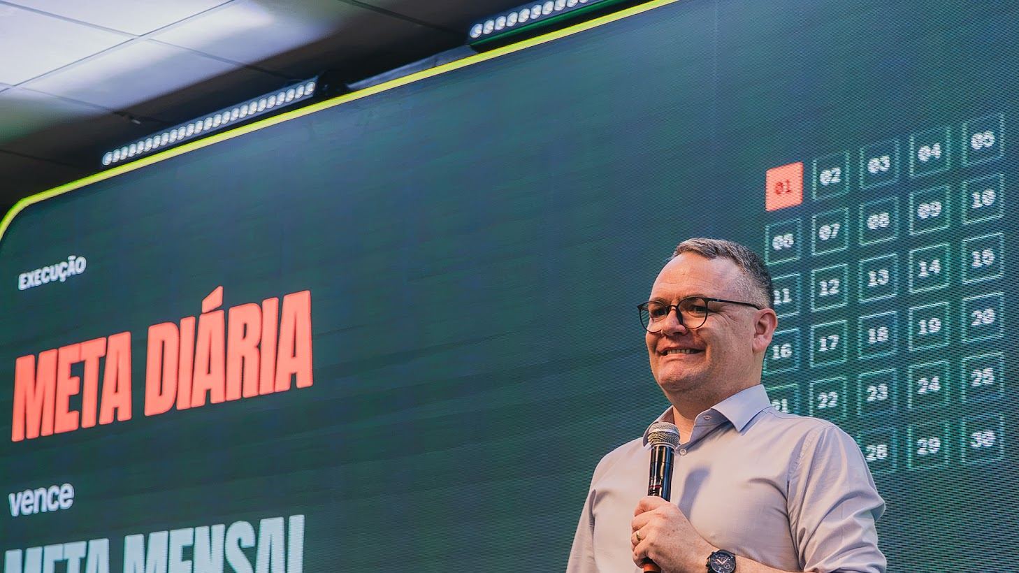 Leandro no palco diante do slide Meta diária vence meta mensal